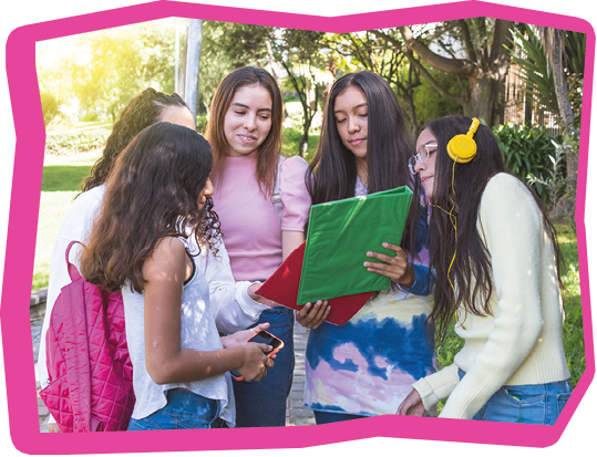 A group of Latina teen girls students with backpacks and notebooks review their homework on their way to high school