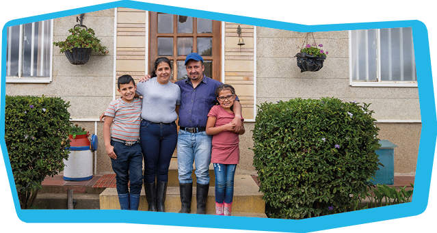 Happy Latin American family smiling in front of their new house and looking at the camera - lifestyle in developing countries concepts