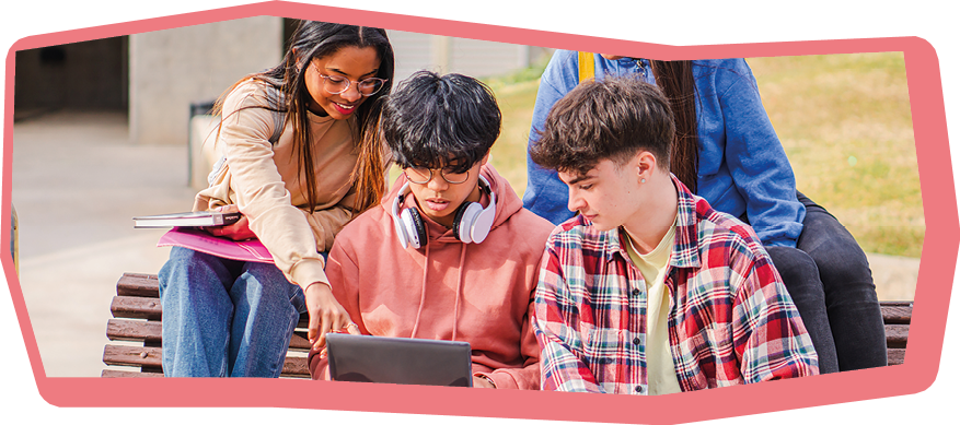 Image of young concentrated students sitting in bench. Looking aside while using laptop computer..High Quality Photo