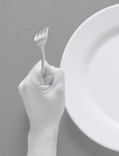 Fork and knife in hands on black background with white plate.