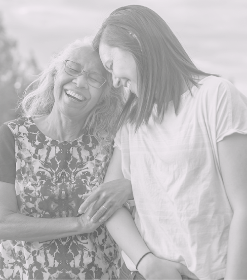 A beautiful senior mom of pacific island descent is walking outdoors with her adult thirty something year old daughter. They are enjoying each others company and soaking in the gorgeous, colorful, sunset.