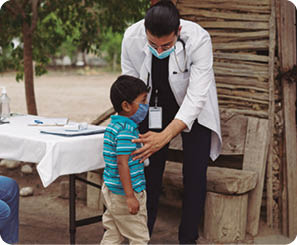A male doctor putting a little boy on a scale in a rural area.