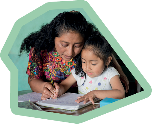 Hispanic mom helping her little daughter do her homework - Mom teaching her daughter to read and write at home - Mayan family at home