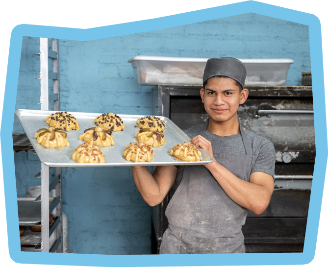 A young Hispanic man is holding a Day of the Dead bread tray. Concept of dia de muertos food