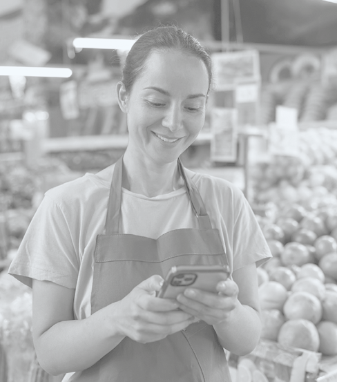 Happy Latin American retail clerk using her phone on her break while working at the supermarket